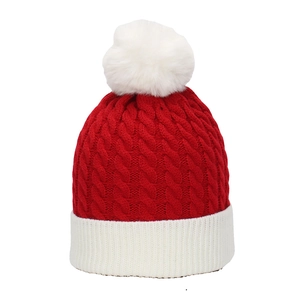 Detail of red cable-knit Christmas hat with white ribbed brim and large faux fur pompom