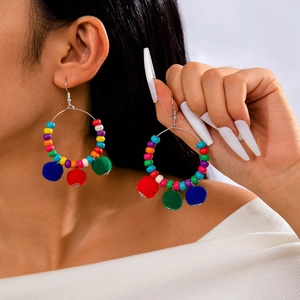 Detail of beaded Christmas hoop earrings with colorful knit balls on a model