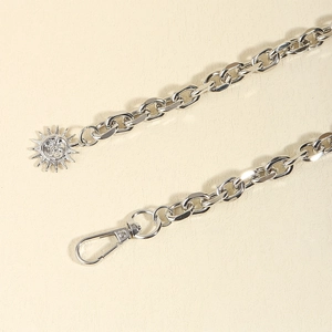 Close-up of silver punk style chain belt with a sun pendant and lobster clasp detail
