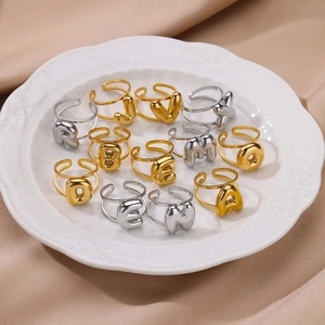 Adjustable stainless steel bubble letter rings in gold and silver on a white tray