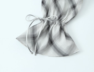 Detail of grey and white plaid cuff with drawstring tie and elegant ruffle trim