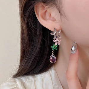 Primo piano dettaglio di orecchini pendenti con fiore in zircone viola sfumato.