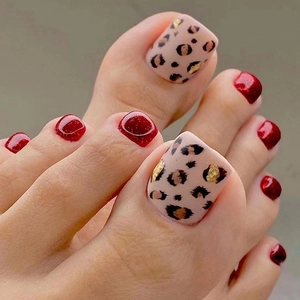Close-up of red glitter and leopard print toe nail art with gold accents