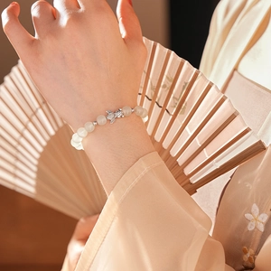 Detail of beaded chalcedony bracelet with silver fish charm on a model's wrist