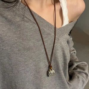 Faux leather bag pendant long necklace with spotted stone texture on grey sweater