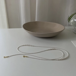 Detail of white pearl chain with gold metal clasps on a minimalist background