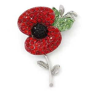 Detail of red rhinestone poppy brooch with black center and green leaves on silver base