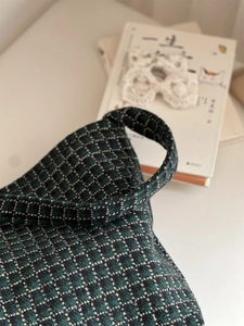 Close-up of the thick wool fabric and stitching on a green plaid shoulder bag