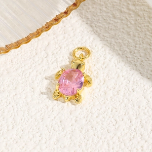 Macro detail of 18k gold plated turtle pendant with a pink oval cubic zirconia stone