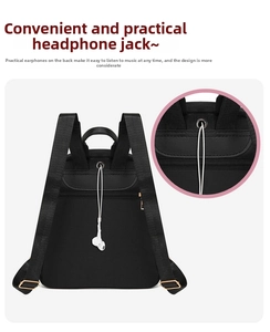Detail view of black oxford backpack showing earphone port and adjustable gold buckles