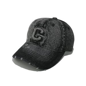 Detailed macro view of distressed denim fabric with C letter embroidery and frayed brim holes