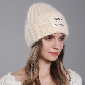 Winter rabbit fur knit beanie in beige with SEASCN 12 patch on grey-blue background