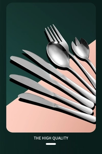 Close-up of polished stainless steel cutlery set on a green and pink background