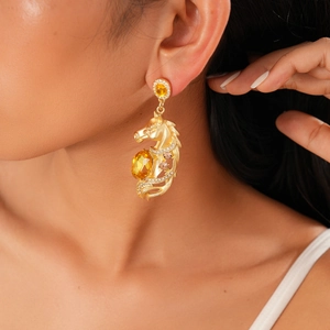 Macro shot of gold horse head earring featuring a large oval yellow gem and rhinestones