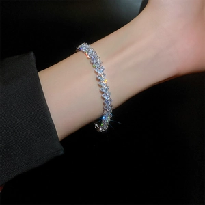 Macro side view of a silver sparkling zircon bracelet worn on a wrist against black background
