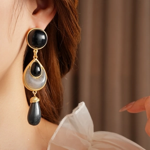 Close-up of vintage golden drop earrings with black and grey gradient resin stones