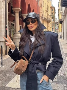 Women stylish dark blue lapel jacket with belt and brown suede crossbody bag in city street