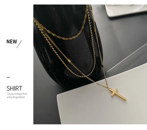 Detail of a triple-layered gold titanium steel necklace featuring a cross pendant