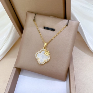 Detailed macro of gold titanium clover necklace with white shell and inlaid diamonds