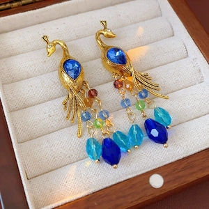 Detail of vintage peacock earrings with blue teardrop crystal and colorful beaded tassels