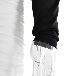 Detailed close-up of ruched white fabric texture and black sleeve on slim fit dress