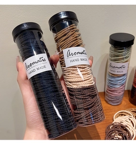 Detail of colorful elastic seamless hair ties in a transparent cylinder with handmade label