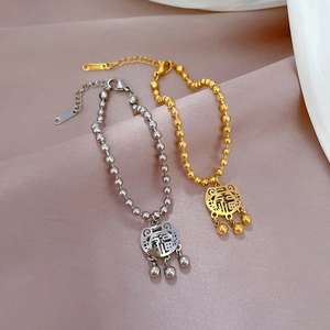 Macro detail of the Fu character and long-life lock charm on a beaded steel bracelet