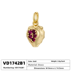 Detail shot of a gold strawberry pendant with red zircon inlay and brass material info