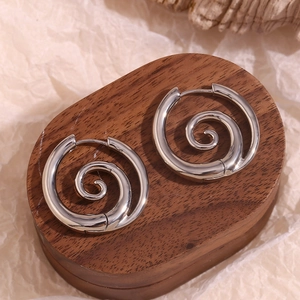 Makroansicht silberner Spiralschneckenohrringe auf dunklem Holz mit poliertem Finish