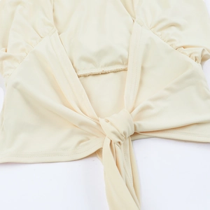 Detailaufnahme des beigen Neckholder-Tops mit dem feinen Bindeknoten und Stoffstruktur