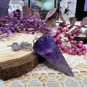 Natural amethyst hexagonal pendulum pendant with silver chain on rustic wood and dried flowers