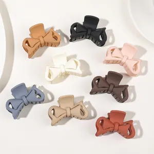 Flat lay of colorful matte bow hair claws in eight assorted neutral and pastel shades