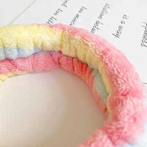 Close-up of soft coral fleece headband with pink yellow and blue gradient stripes