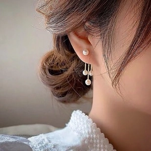 Detail view of gold drop earrings featuring multiple pearls on elegant long bars
