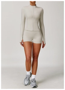 Detail of light gray yoga jacket with thumbholes and high-waist athletic shorts