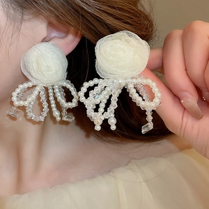 Macro detail of fabric flower earrings with pearl bow drop on a model's ear