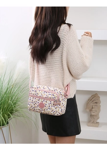 Close-up of a women's crossbody bag with colorful dots print and pink zippers