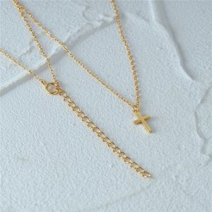 Detail shot of golden cross necklace showing adjustable chain links and O-chain texture