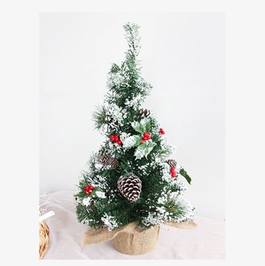 Mini tabletop Christmas tree with snow-dusted needles, red berries, and pine cones