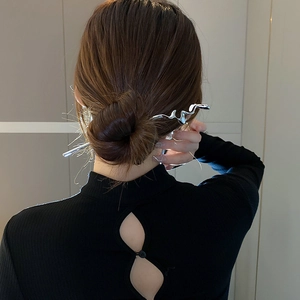 Detail view of fluid metal hair pin in silver finish styled on a brunette hair bun