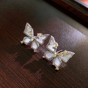 Macro detail of French style zircon flower earrings with silver metal and butterfly design