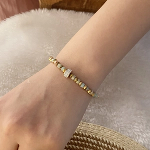 Close-up of vintage beaded heart bracelet with light green stones on a soft beige background