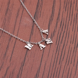 Detailed view of silver MAMA letter pendants on a fine link chain on dark wood