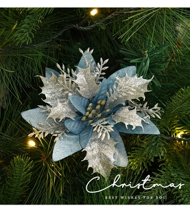 Close-up of blue and silver glitter poinsettia flower on a lit Christmas tree branch