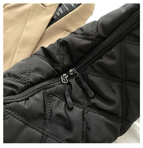 Detail of smooth double zipper design on black quilted diamond pattern handbag