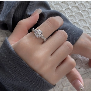 Close-up of sparkling zircon ring with twisted hollow band on model's finger