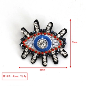 Detailed view of evil eye brooch with blue crystals and red beads, 58mm x 56mm size