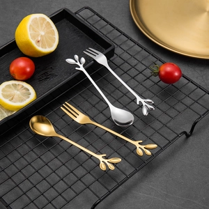 Close-up of golden and silver leaf-shaped stainless steel dessert spoons and fruit forks