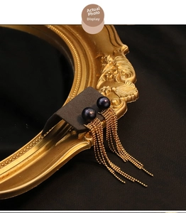 Detailed side view of 18k gold plated black pearl earrings with long beaded tassels