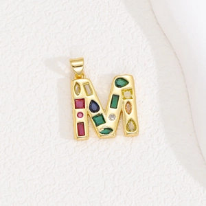 Detailed macro view of gold letter M pendant with colorful zircon stones inlay